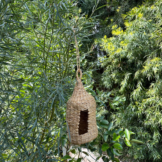 Photo of the cylinder birdhouse available. hanging on a tree. different angle.