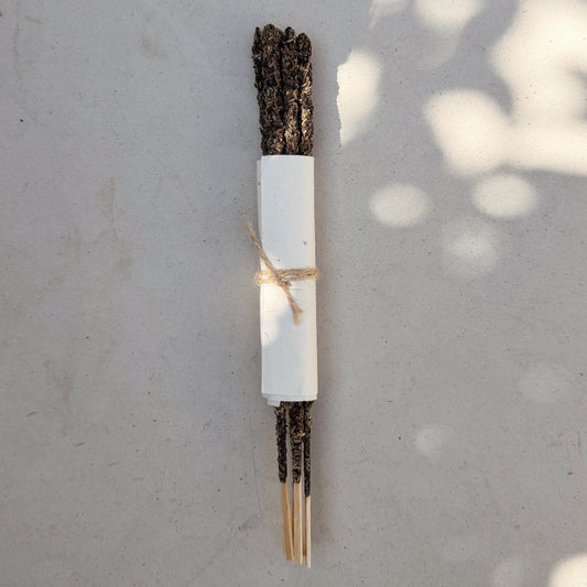 Incense stick bundle of 6 on a gray surface with leaf shadows