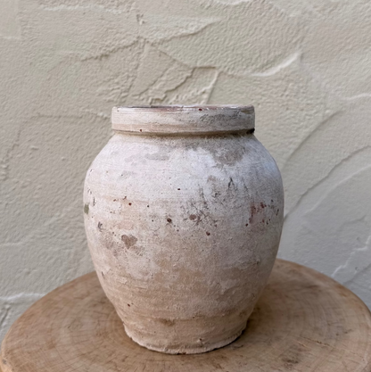 Terracotta pot on a wooden stand against a textured wall